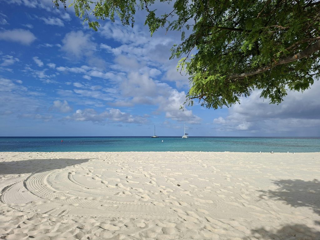 Plage de sable blanc et yachts au mouillage dans les Caraïbes