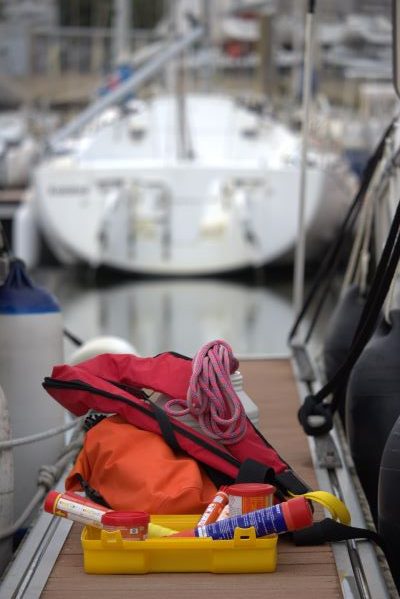 Équipements de sécurité nautique disposés sur le pont d’un bateau, incluant gilet de sauvetage et matériel de secours.